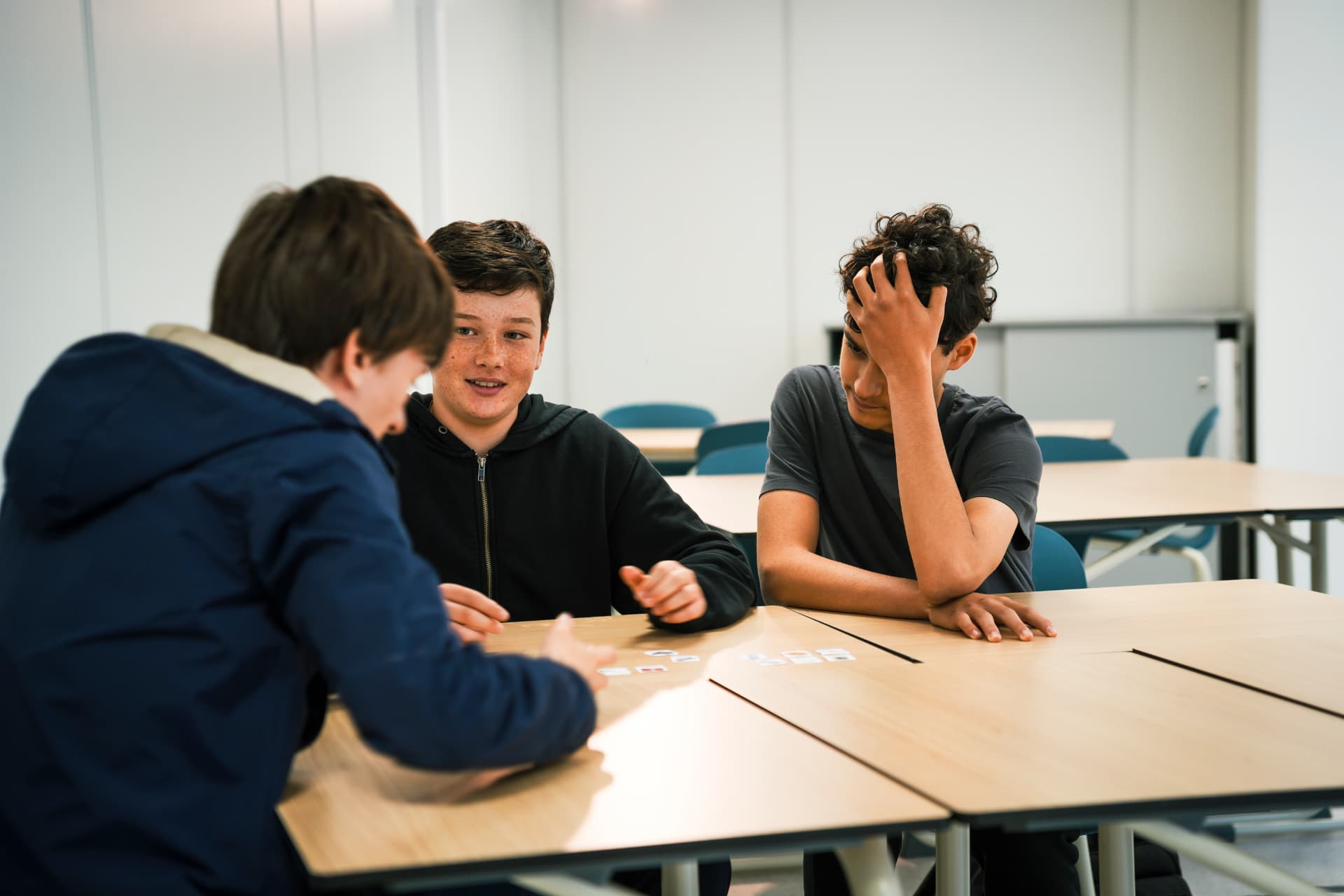Three students in conversation around a classroom table