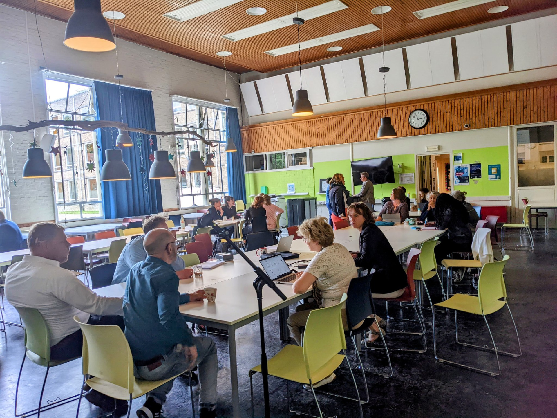 Teachers seated around tables listening during a staff training session