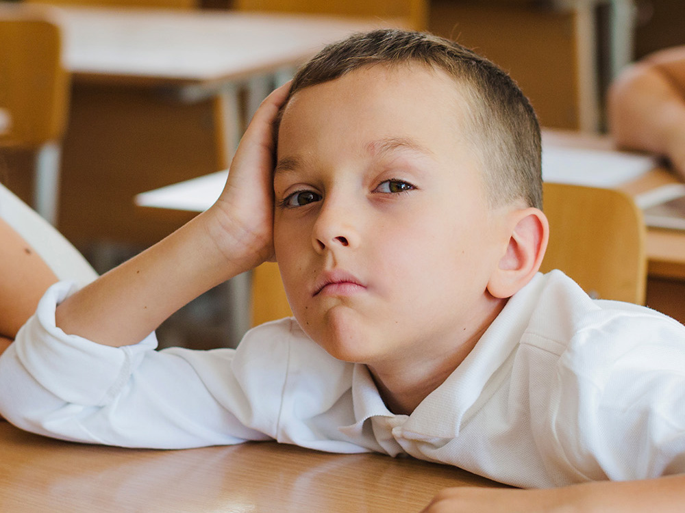 bored child sitting in class waiting for school to be over