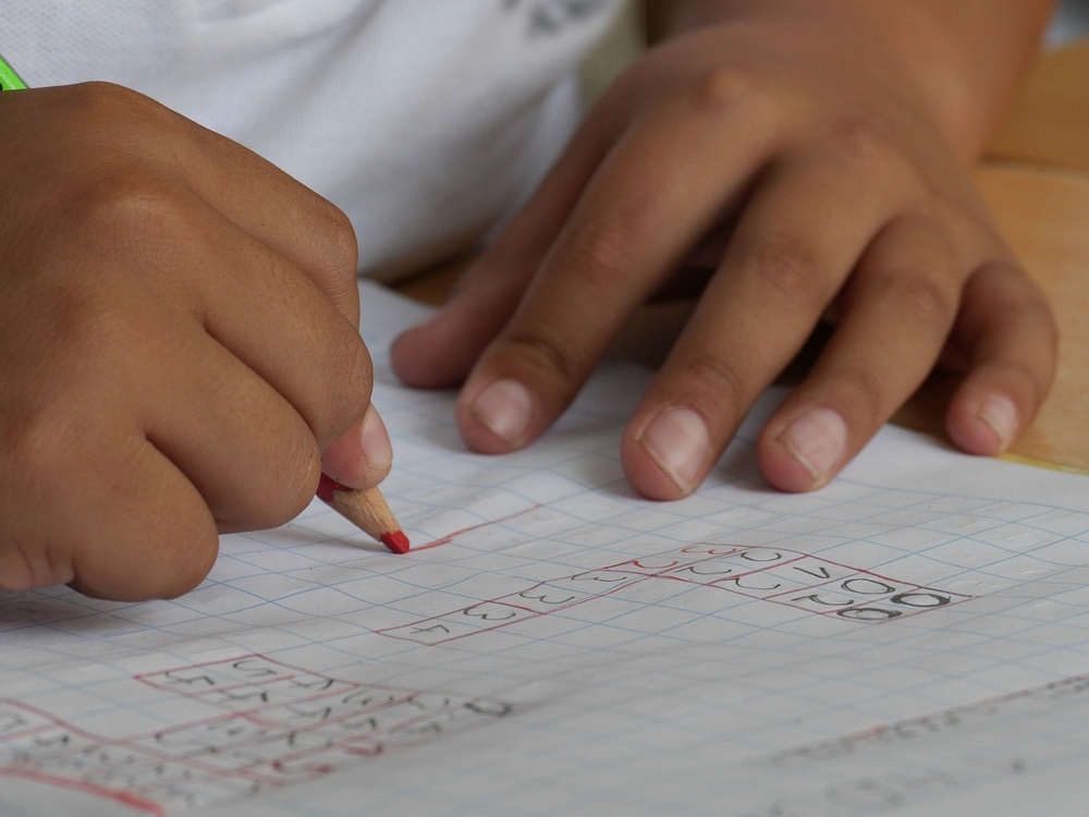a child doing math homework with a red pencil