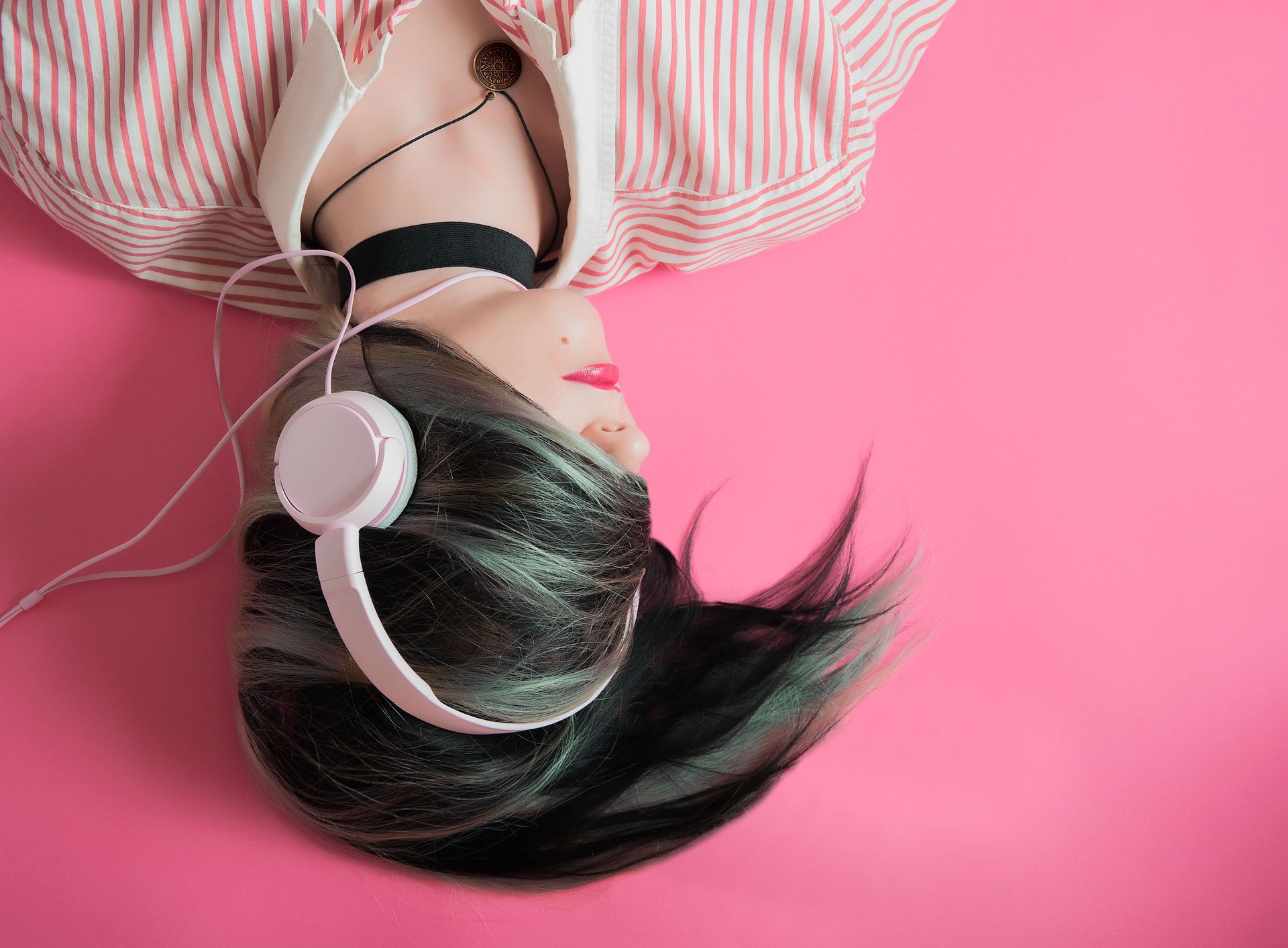 A teenage girl lying down listening to a podcast
