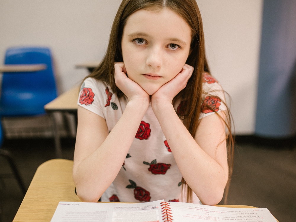 an underachieving girl in school sitting with her notebook,k waiting for the class to be over